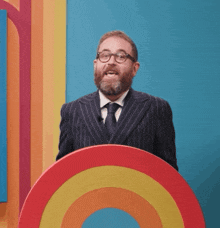 a man in a suit and tie is standing behind a rainbow