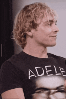 a man with blonde hair is wearing a black shirt with the word adels on it