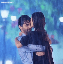 a man and a woman are hugging in the rain and kissing .