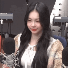 a woman with long black hair stands in front of a microphone with a keyboard in the background