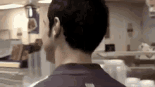 a man in a purple shirt is standing in a restaurant looking at something .