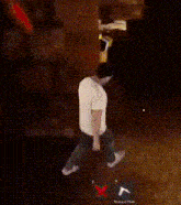 a man in a white shirt is dancing in a dark room with a yellow light behind him