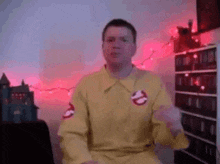 a man in a yellow ghostbusters costume is sitting in a chair in a room .