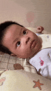 a baby is laying on a bed with a starfish on the pillow