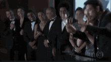 a group of people in tuxedos are standing in a line