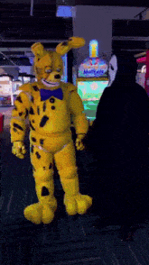 a person in a yellow bunny costume is standing next to a person in a black hoodie with a mask on .