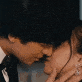 a man in a tuxedo is kissing a woman in a white shirt