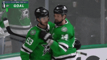 two hockey players wearing green jerseys with the number 53 and 14 hugging each other