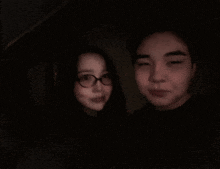 a man and a woman are posing for a photo in the dark