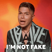 a man in a suit says " i 'm not fake " in front of a red background