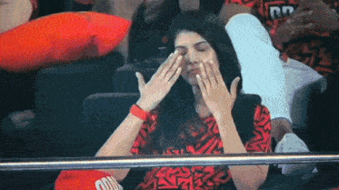 a woman covering her face with her hands while wearing a red shirt that says ' chicago ' on it