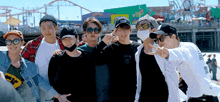 a group of young men are posing for a picture in front of a roller coaster at an amusement park .