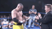 a man in a wrestling ring is holding a belt and talking to another man