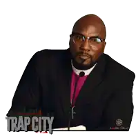 a man in a black suit and purple tie stands in front of a microphone with trap city written on it