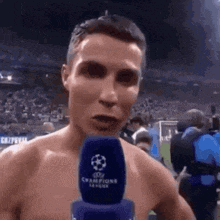 a shirtless man is talking into a microphone while standing on a soccer field .