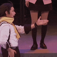 a man with a scarf around his neck is reaching out to a woman 's leg