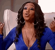 a woman in a blue dress is sitting in a chair with her hands in the air .