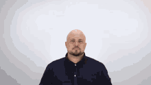 a bald man with a beard is wearing a black shirt
