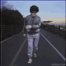 a man is walking down a road with a gif run.com watermark