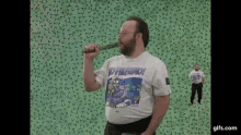 a man with a beard wearing a shirt that says no pregnancy is holding a stick .