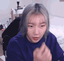 a girl with blonde hair is wearing a blue shirt and making a funny face