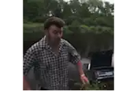 a man in a plaid shirt is kneeling in front of a lake .