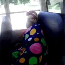 a person sitting on a bus with a polka dot blanket
