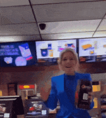 a woman in a blue suit is standing in front of a counter in a fast food restaurant