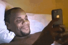 a man is laying in bed looking at his phone .