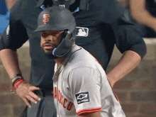 a baseball player wearing a san francisco uniform stands in front of an umpire