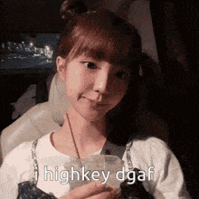 a girl holding a cup with the words " i highkey dgaf " written on it