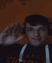 a young man wearing headphones is waving at the camera