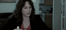 a woman is sitting at a table with a small white container in front of her