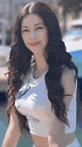 a woman with long black hair is wearing a white crop top and white shorts .