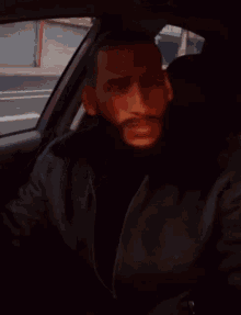 a man with a beard is sitting in a car and holding a cell phone