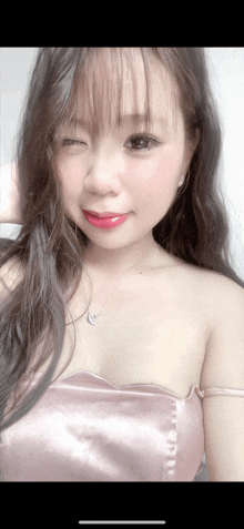 a woman wearing a pink dress and a heart shaped necklace