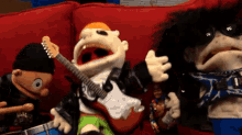 a group of puppets are playing guitars and drums on a couch
