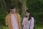 a man and a woman are standing next to each other under a tree .