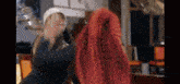a woman is covering her face with a red cloth while standing next to another woman .