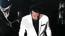 a man in a white suit stands in front of a spider web