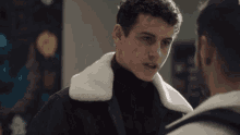 two men are standing next to each other and one has a fur collar on his jacket .