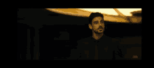 a man in a suit and tie says " shall i continue " in a dark room