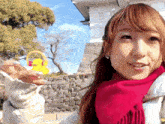 a woman in a pink scarf holds a yellow rubber duck with headphones on it