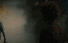 a man is standing in a dark room with smoke coming out of the window .