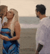 a woman kisses another woman on the cheek while a man watches