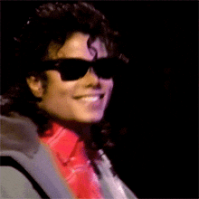 a man wearing sunglasses and a red shirt smiles