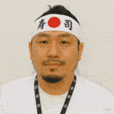 a man wearing a headband with chinese characters on it is eating a bowl of soup