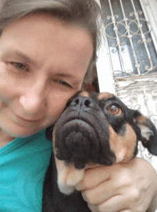 a woman in a blue shirt is holding a dog