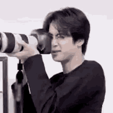 a man is holding a camera and looking through it .