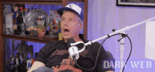 a man wearing a hat is sitting in front of a microphone in a room .
